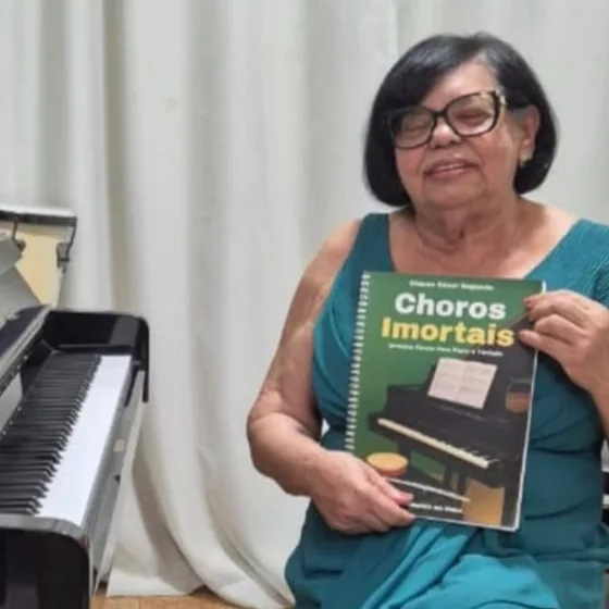 Cliente sentada ao piano com o livro Choros Imortais